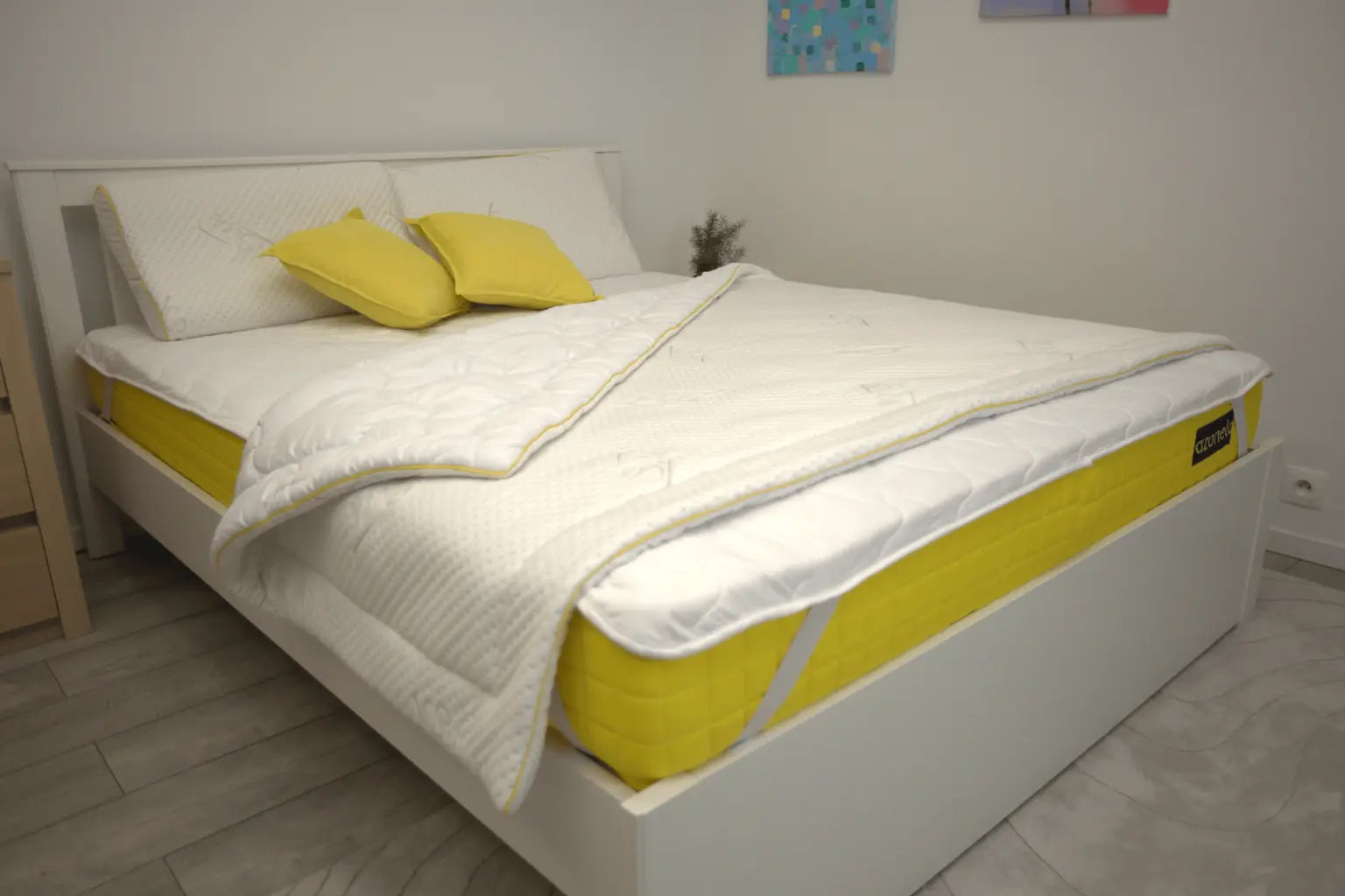 Matrace 1+1 akcia. Žltý matrac Azonelo Yellow 21 cm ustlaný na bielej posteli v modernej spálni.