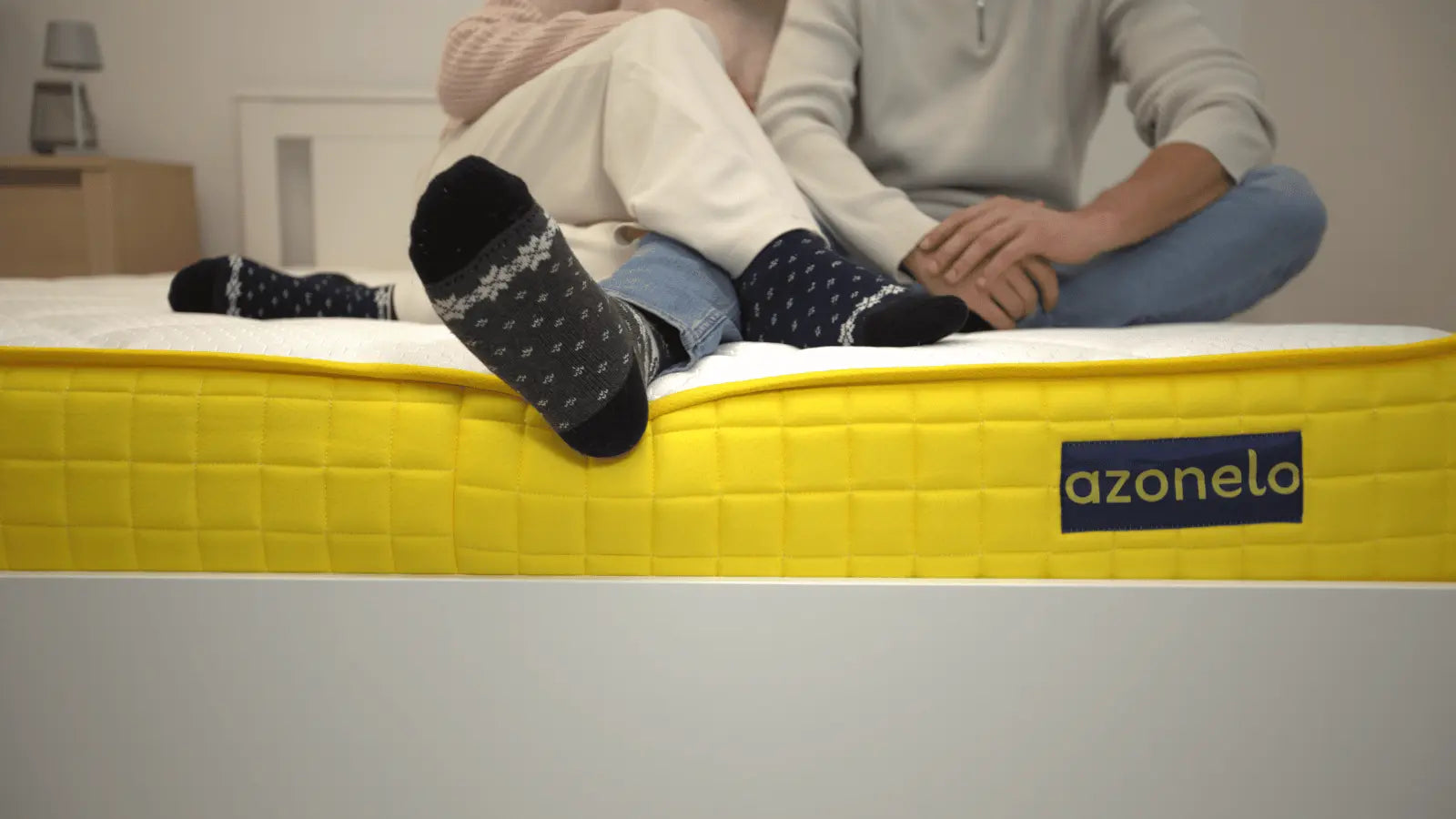 Mladý pár v pekných ponožkách pohodlne sedí na kvalitnom slovenskom matraci Azonelo a testuje jeho komfort.