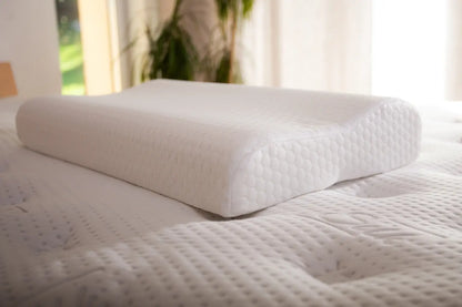 Detailný záber na biely anatomický vankúš Azonelo položený na posteli. Zblízka tu vidieť jeho typický ergonomický tvar dvoch vĺn pre správnu podporu krčnej chrbtice, ako aj štruktúru čistého bieleho poťahu, v ktorom sa ukrýva mäkká pamäťová pena.
