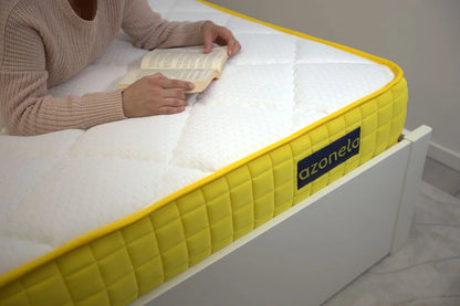 Osoba pohodlne relaxuje s knihou na 21 cm vysokom matraci Azonelo Yellow, ktorý má prešívaný biely poťah a výrazný žltý bok