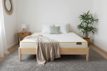 Moderne zariadená spálňa s drevenou posteľou, na ktorej je matrac Azonelo Original ustlaný s vankúšmi a béžovou prikrývkou.