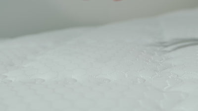 Ruka stláča 7-zónový matrac Azonelo Classic a demonštruje jeho strednú tvrdosť.