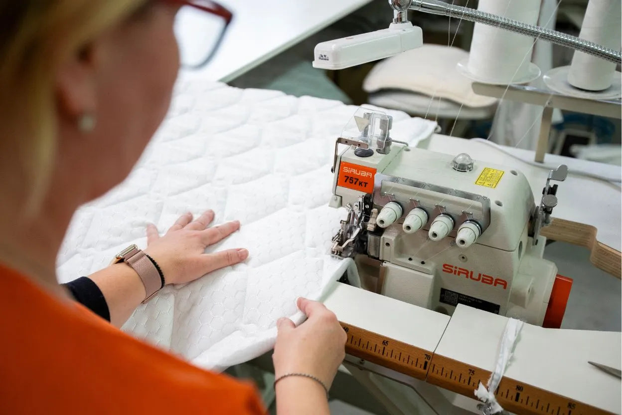 Ručné šitie poťahu matraca Azonelo na profesionálnom šijacom stroji na Slovensku. Detailna fotografia zdôrazňuje precíznu remeselnú výrobu slovenských matracov Azonelo pre kvalitný spánok a pohodlie.